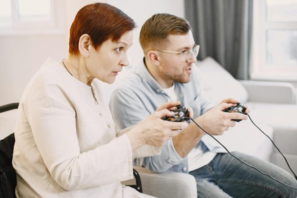 A senior and young adult playing video games together in a cozy living room setting.