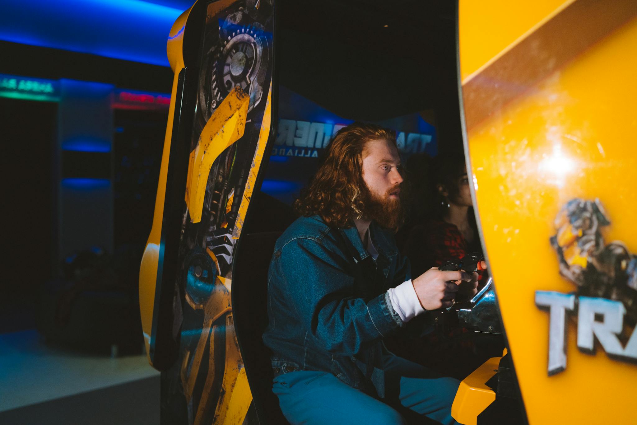 Bearded man passionately gaming at an arcade, focused and engaged.