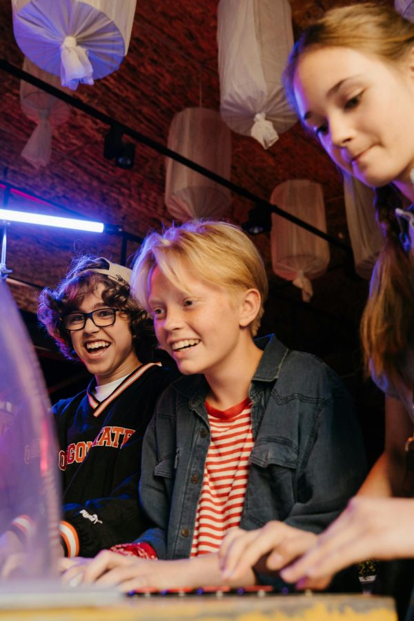 Group of teenagers having fun playing arcade games indoors with cheerful expressions.