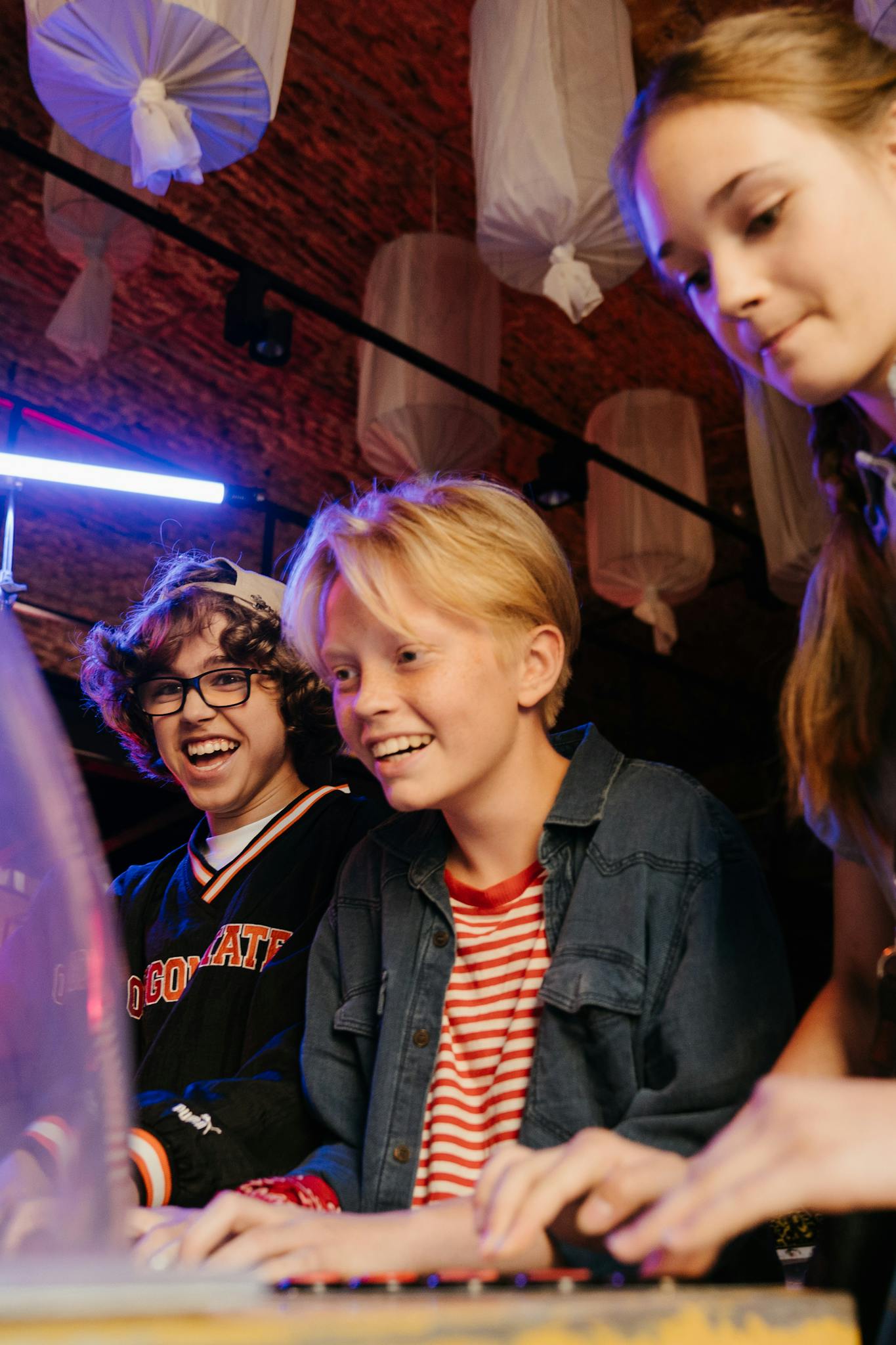 Group of teenagers having fun playing arcade games indoors with cheerful expressions.