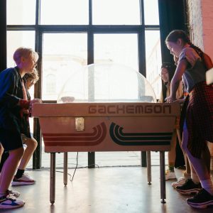 Group of teenagers playing air hockey in a lively arcade environment, enjoying a fun and social atmosphere.