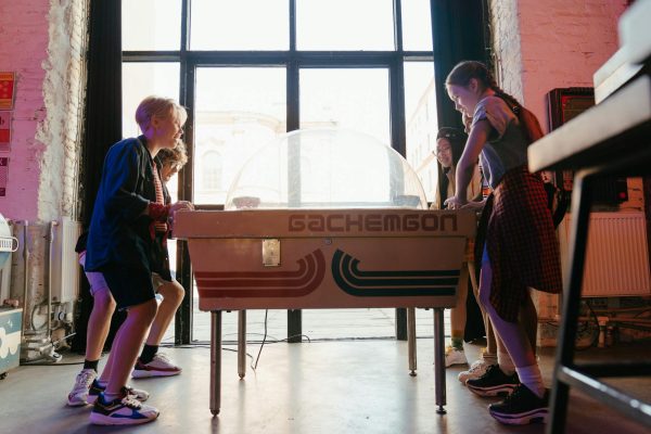 Group of teenagers playing air hockey in a lively arcade environment, enjoying a fun and social atmosphere.